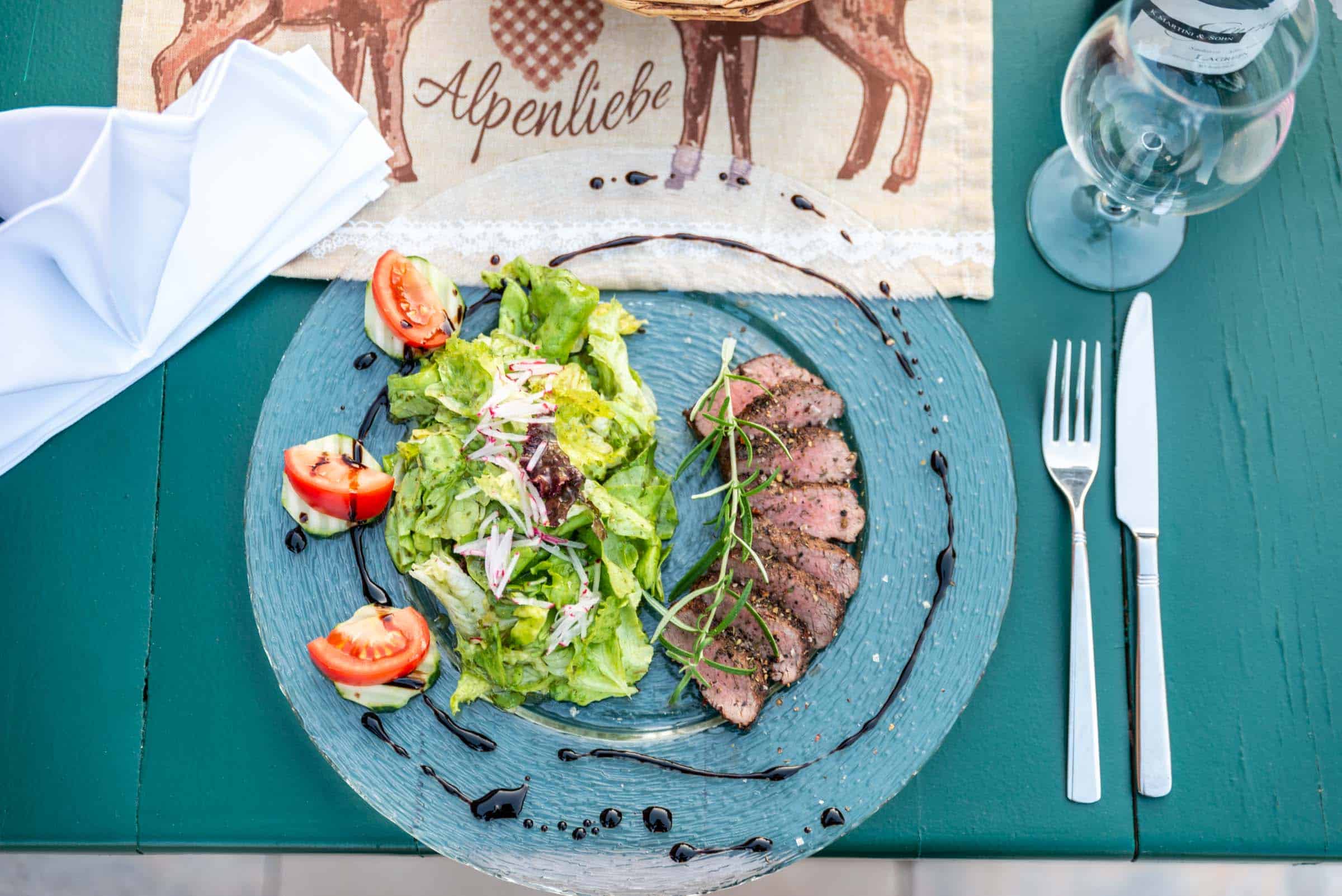Helles Steak mit Rucola-Salat und Tomaten, serviert auf einem stilvollen blauen Teller. Perfekte Präsentation für kulinarische Genussmomente.
